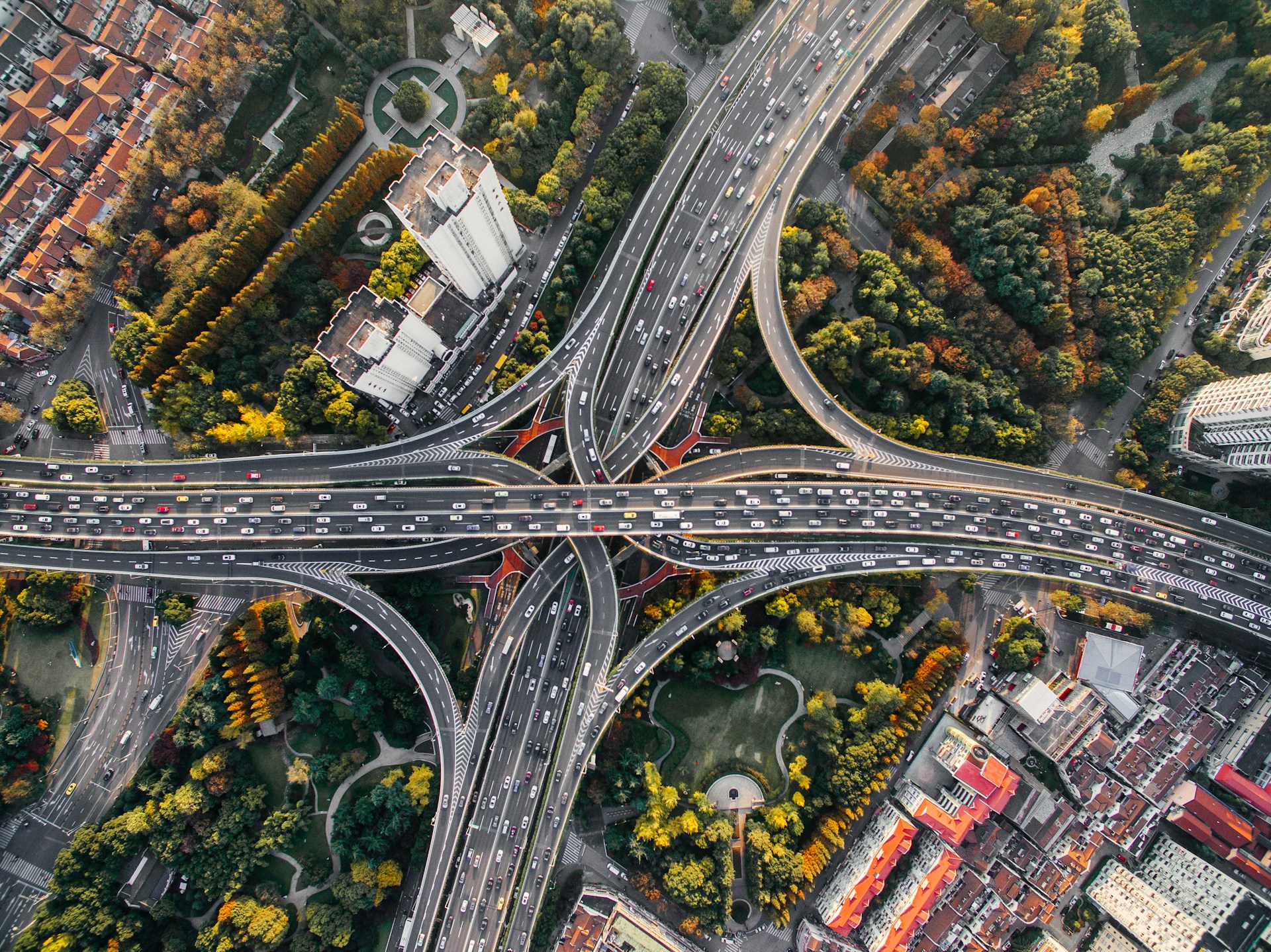Luftaufnahme eines komplexen, mehrstöckigen Autobahnkreuzes in einer chinesischen Metropole mit dichtem Verkehrsaufkommen; die erhöhte Perspektive ermöglicht trotz des scheinbaren Chaos eine klare Übersicht über die Verkehrsströme und Verbindungen.