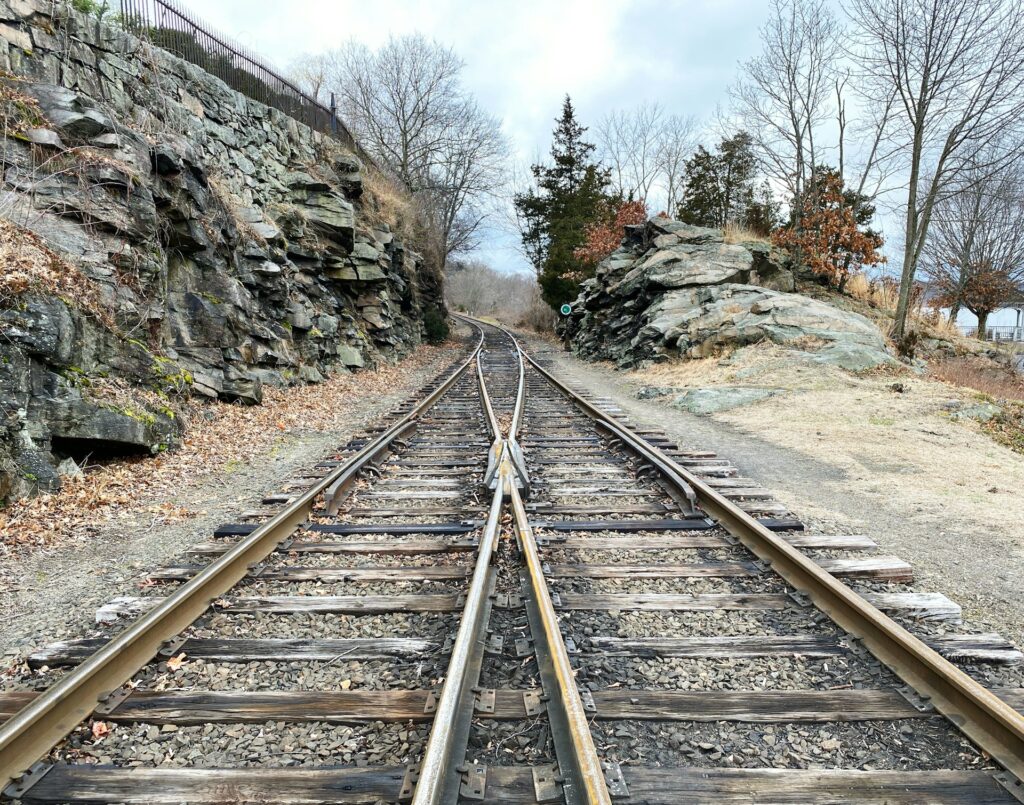 Zwei parallel verlaufende Eisenbahnschienen führen aus zwei Richtungen zusammen und bilden im weiteren Verlauf einen gemeinsamen Schienenstrang.